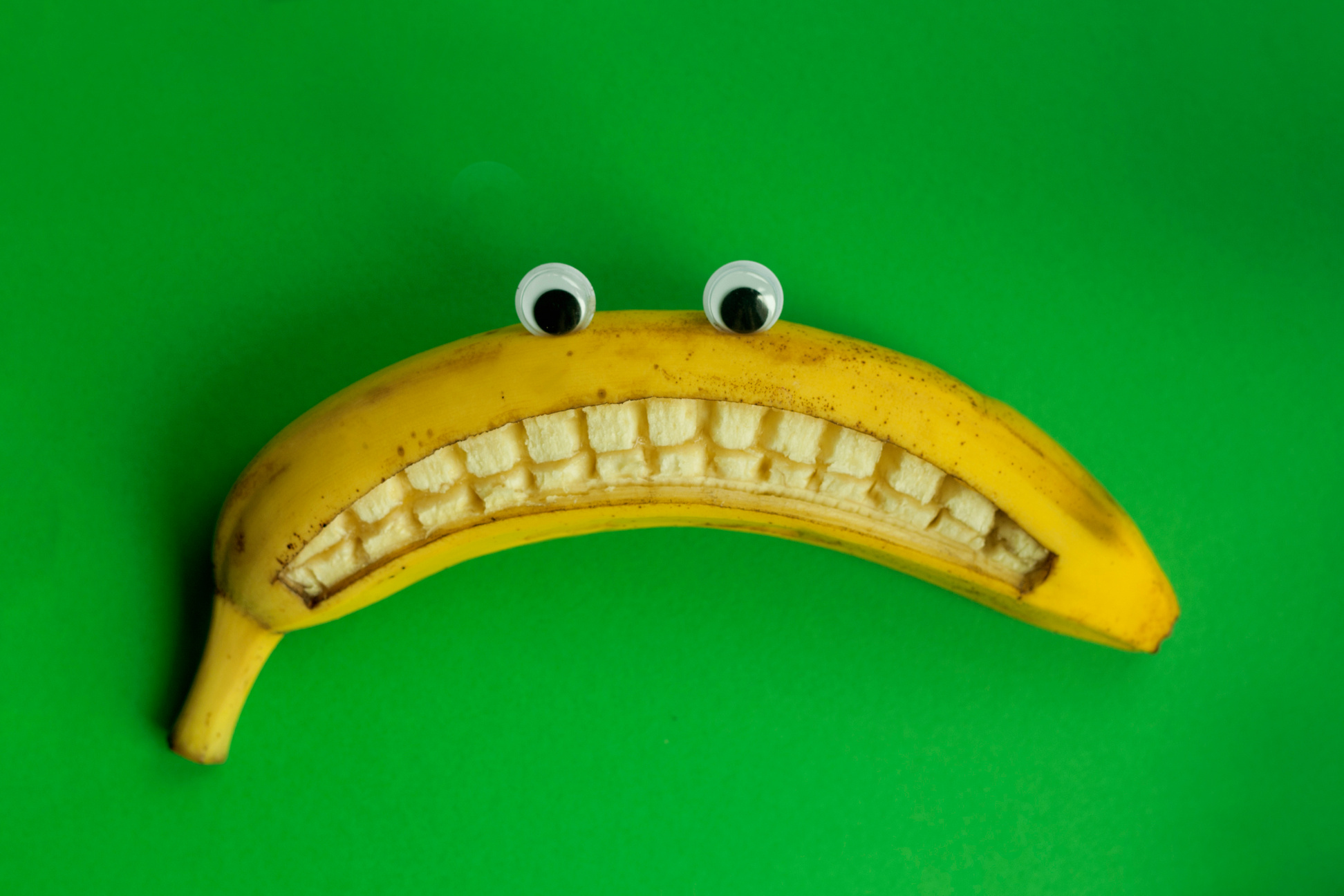 Sad banana with eyes on a green background